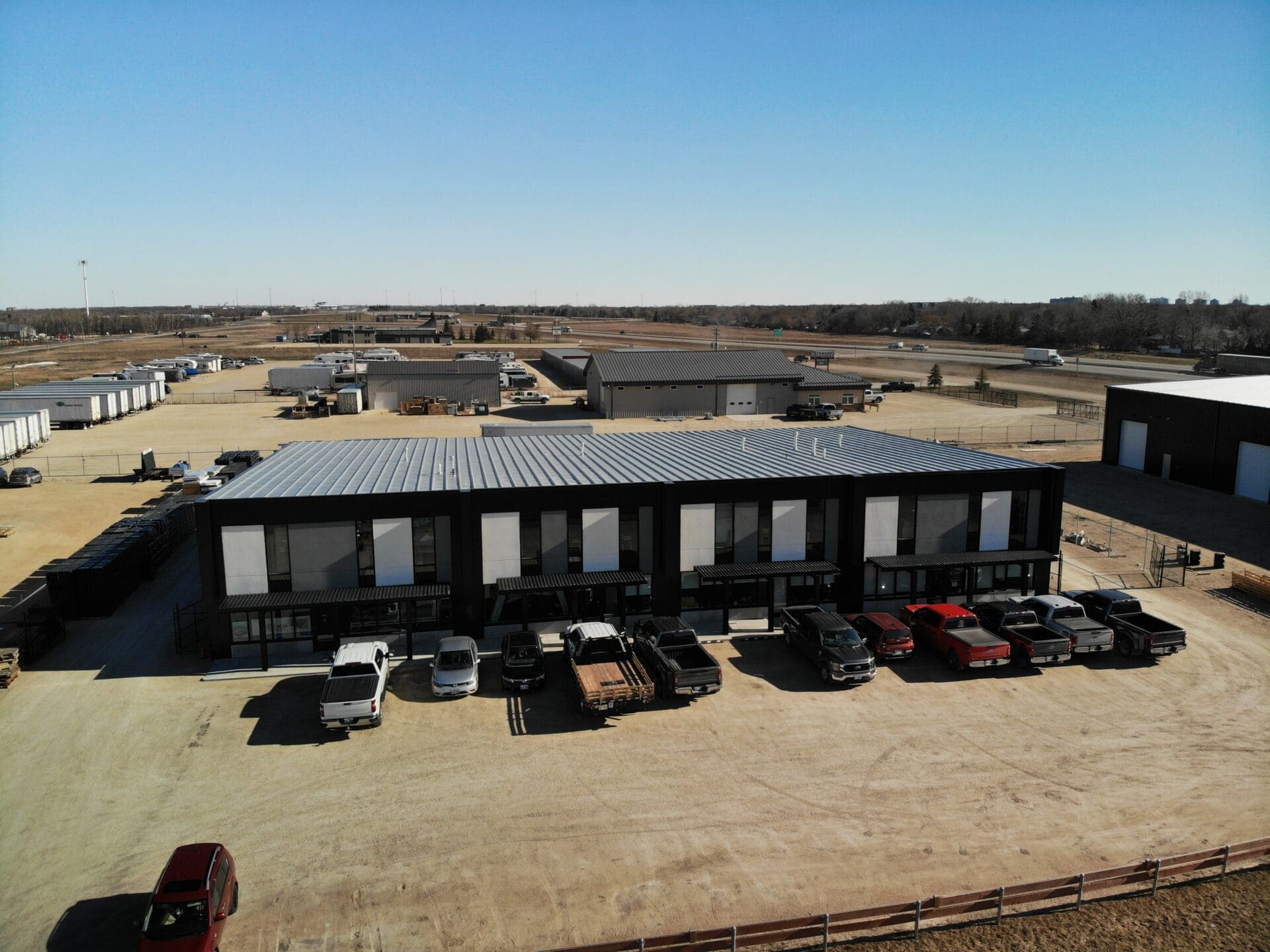 A commercial pre-engineered steel structure with several vehicles parked in front.