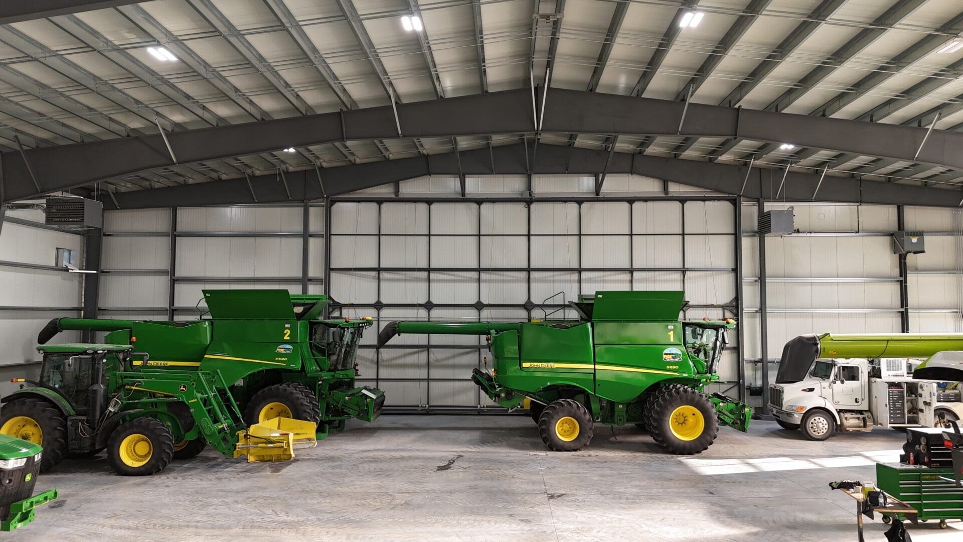 Large farming machinery lined up end-to-end inside a pre-engineered steel structure